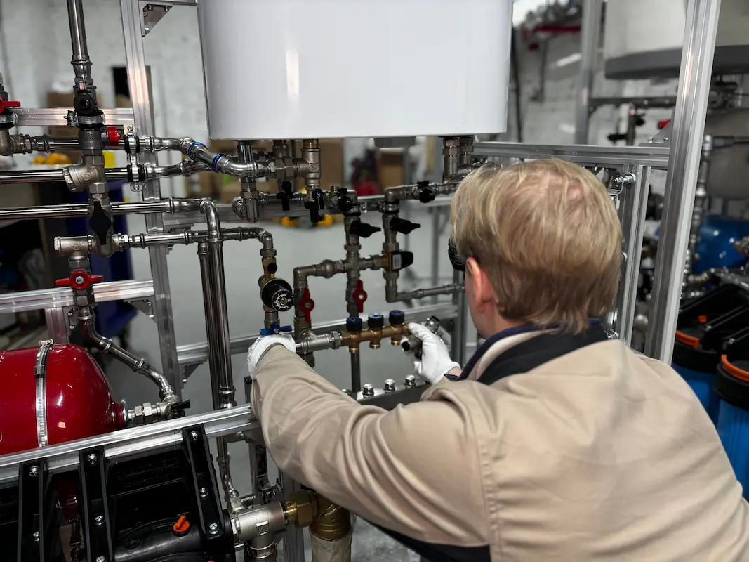 Technician servicing a multi-valve plumbing and water pressure system in a workshop