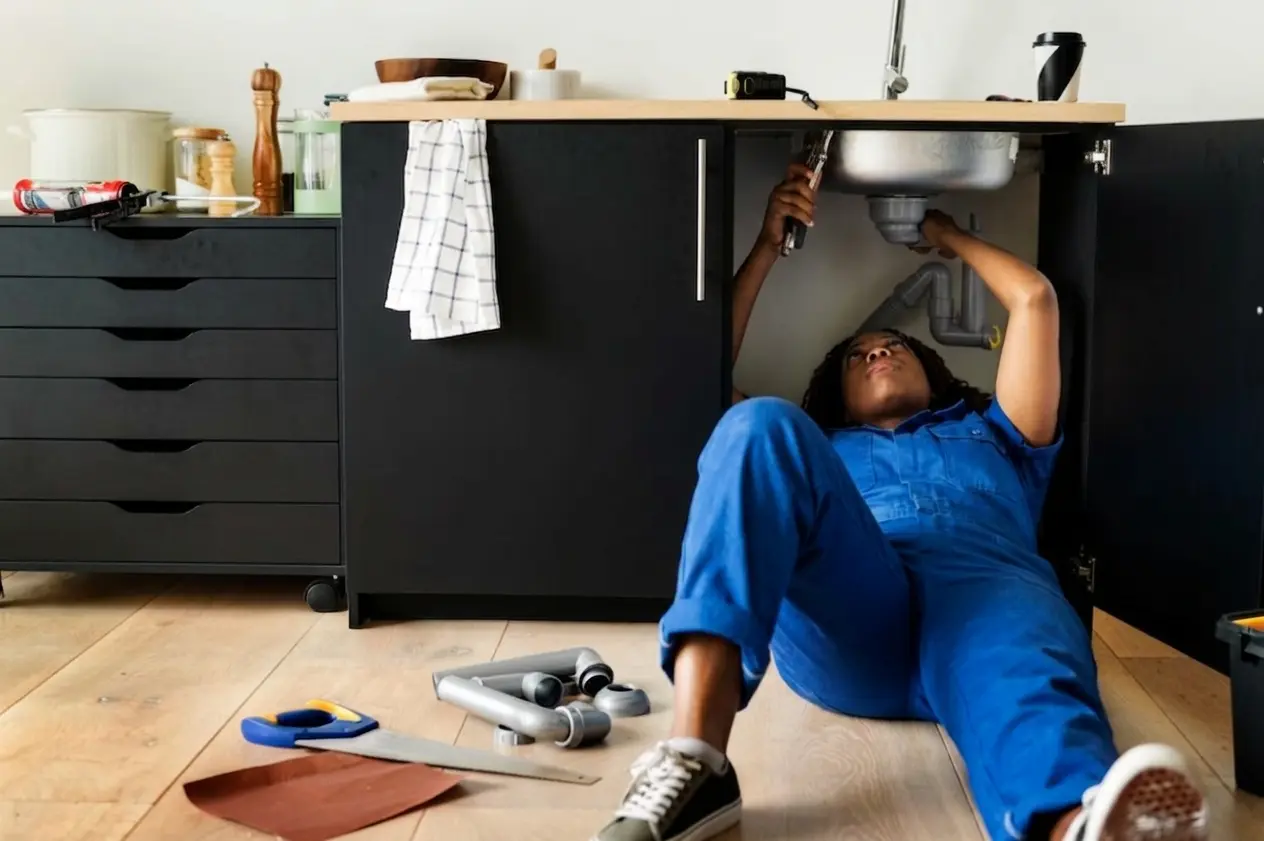 Plumber repairing pipes under a kitchen sink as part of plumbing services in Dubai