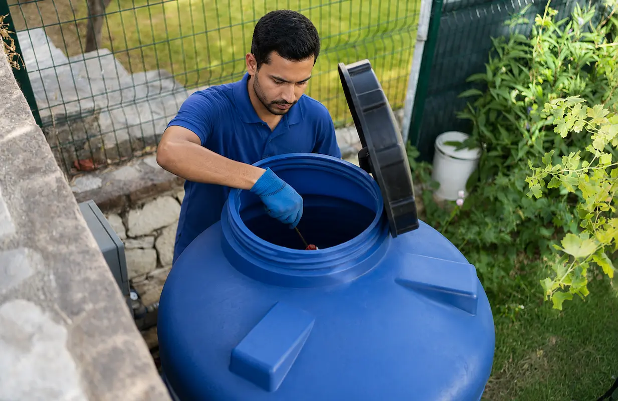 Technician inspecting the inside of a plastic water tank during a maintenance check